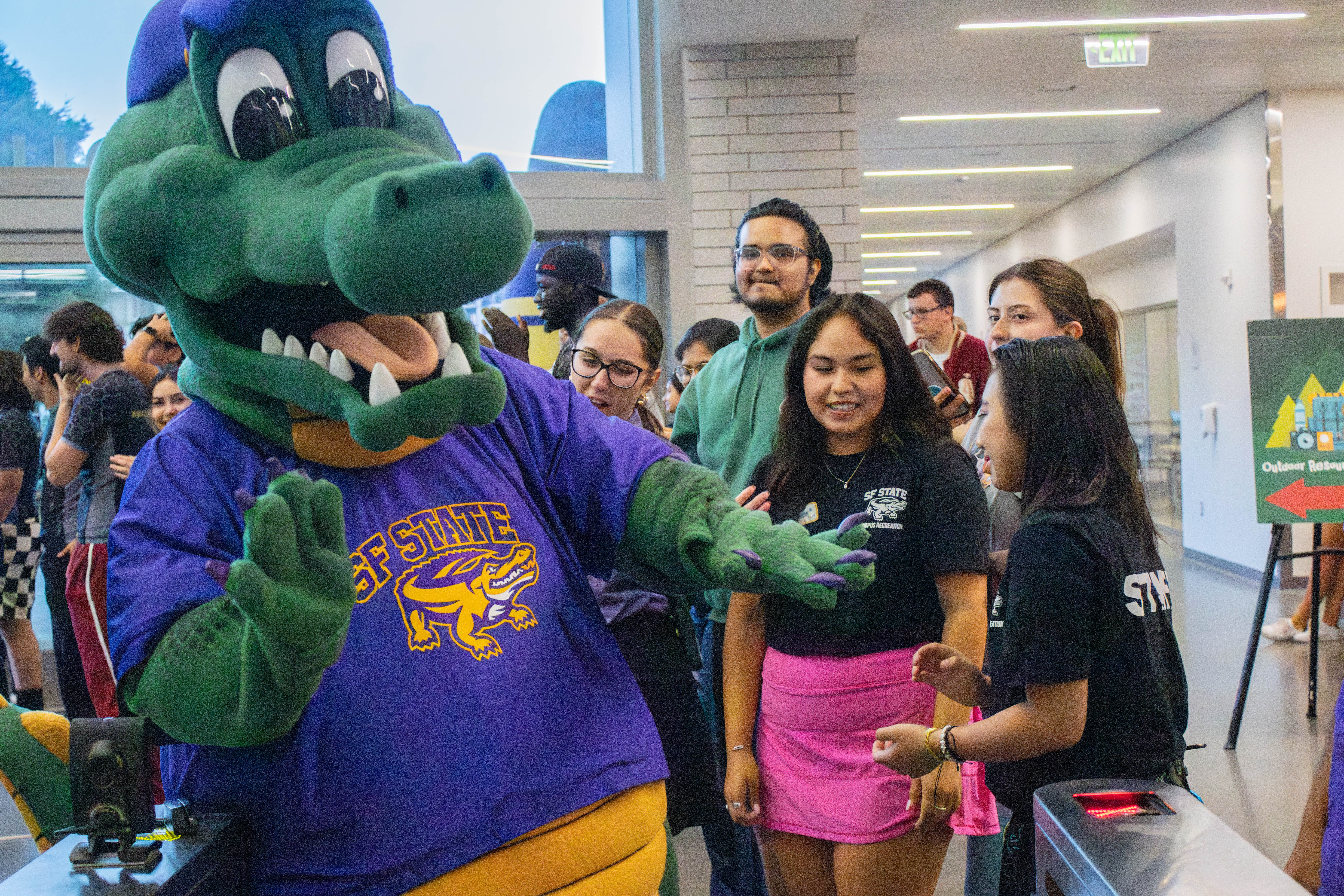 Ali the Gator mascot moving through a crowd of happy students and staff