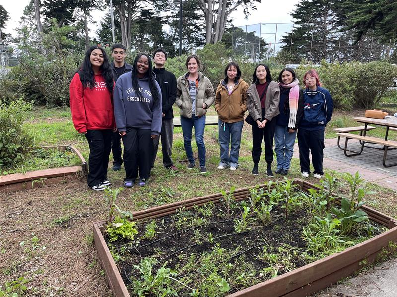 students standing near a small planter box and garden.