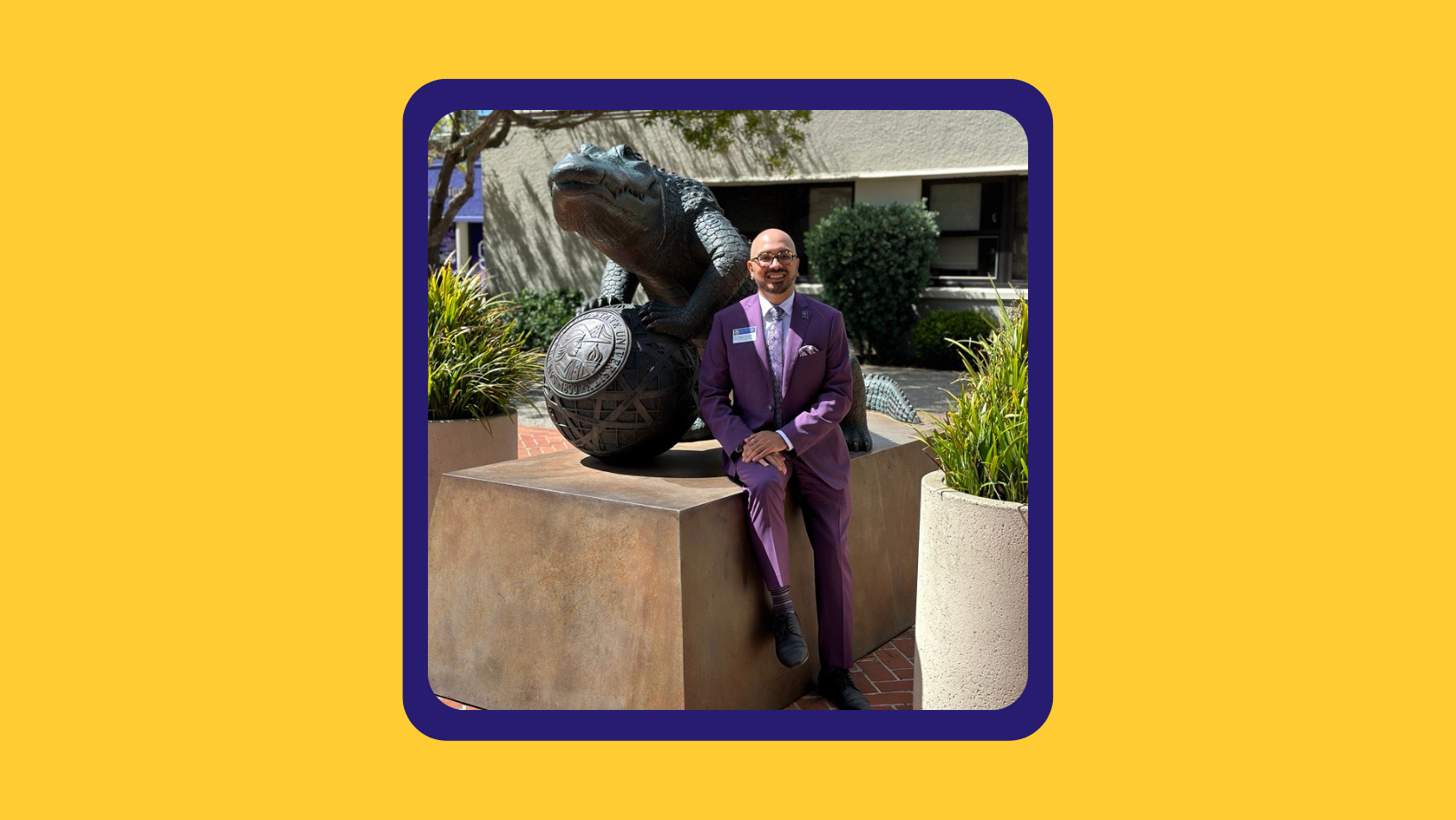 Dean Miguel, in a purple suit posed next to the bronze gator statue in Nessar Plaza