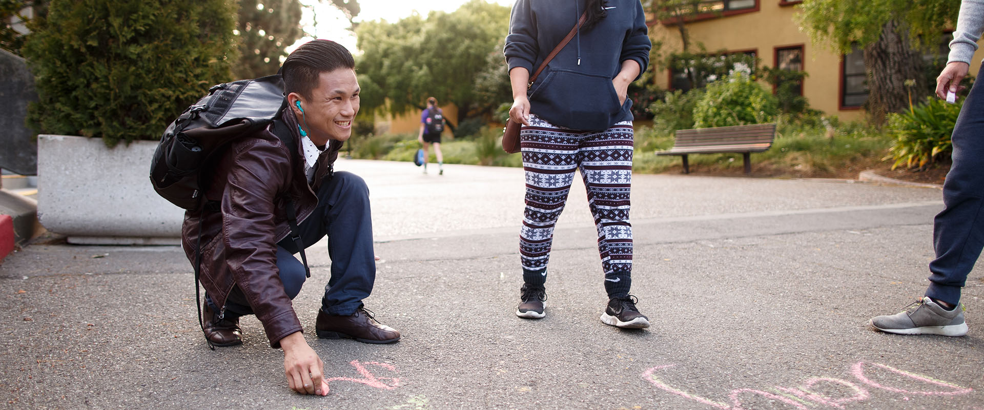 student chalking on a sidewalk/pathway