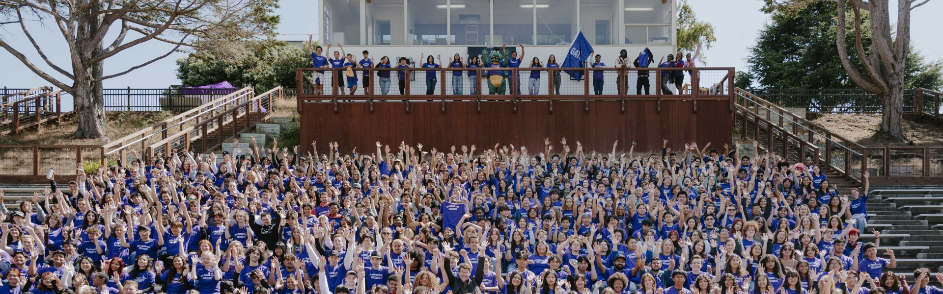 a crowd of students sitting and cheering wearing all purple